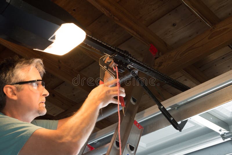De professionele automatische van de de openerreparatie van de garagedeur van de de diensttechnicus werkende close-up stock afbeelding De professionele automatische van de de openerreparatie van de garagedeur van de de diensttechnicus werkende close-up stock afbeelding