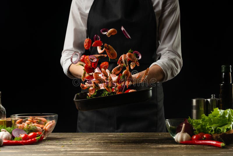De professionele chef-kok wierp garnalen met groenten op de grillpan, bevriezend in motie, concept zeevruchten en gezond voedsel royalty-vrije stock foto's De professionele chef-kok wierp garnalen met groenten op de grillpan, bevriezend in motie, concept zeevruchten en gezond voedsel royalty-vrije stock foto's