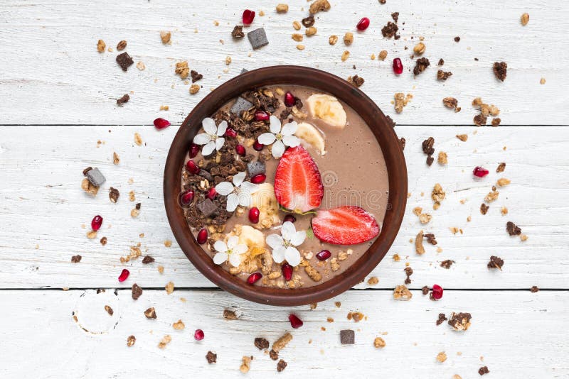 De proteïne van de cacaobanaan smoothie werpt met van de van de chocoladegranola, aardbei en granaatappel zaden met bloemen worde royalty-vrije stock afbeelding De proteïne van de cacaobanaan smoothie werpt met van de van de chocoladegranola, aardbei en granaatappel zaden met bloemen worde royalty-vrije stock afbeelding