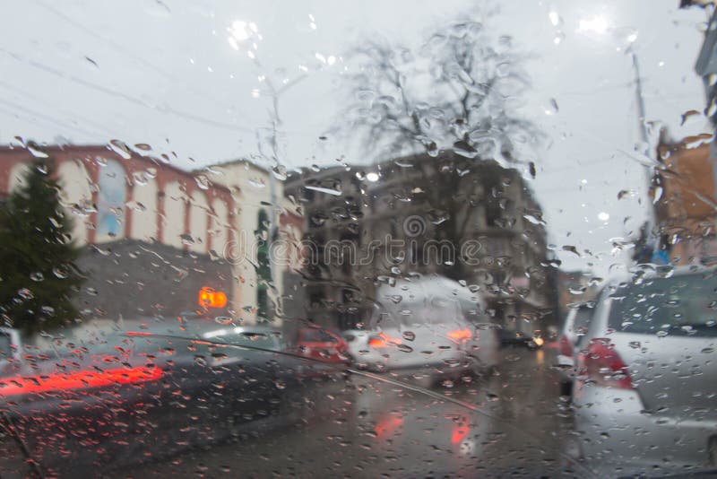 De regenachtige dagen, Avond, regendalingen op het venster met verkeer vertroebelen Onscherp autosilhouet stock fotografie De regenachtige dagen, Avond, regendalingen op het venster met verkeer vertroebelen Onscherp autosilhouet stock fotografie