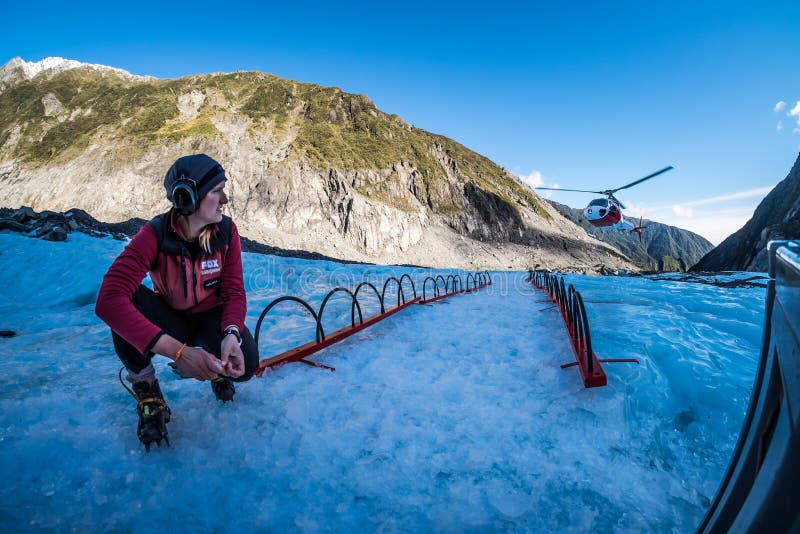 De reisgids wacht op voor een helikopter bij vosgletsjer, Nieuw Zeeland stock foto's De reisgids wacht op voor een helikopter bij vosgletsjer, Nieuw Zeeland stock foto's