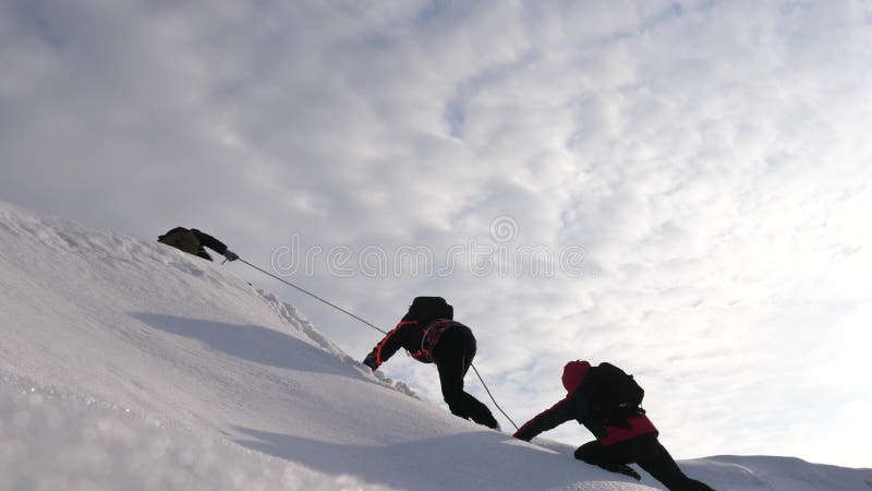 De reizigers beklimmen kabel aan hun overwinning door sneeuwhelling in een sterke wind De toeristen in de winter werken samen als stock foto's De reizigers beklimmen kabel aan hun overwinning door sneeuwhelling in een sterke wind De toeristen in de winter werken samen als stock foto's