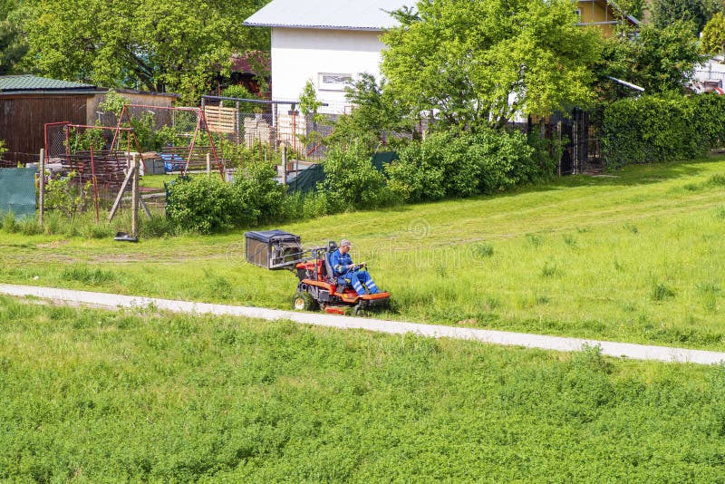 De rijpe snijder van het mensen drijfgras in een zonnige dGardener die een berijdende grasmaaimachine in gardenay drijven Arbeide royalty-vrije stock afbeeldingen De rijpe snijder van het mensen drijfgras in een zonnige dGardener die een berijdende grasmaaimachine in gardenay drijven Arbeide royalty-vrije stock afbeeldingen