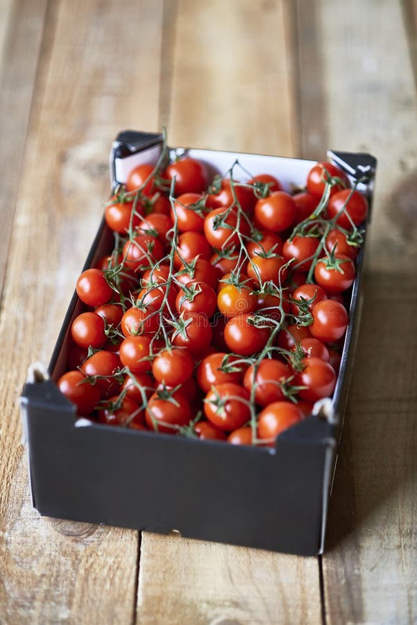 De rijpe takken van Kersentomaten in een doos van het marktkarton stock fotografie De rijpe takken van Kersentomaten in een doos van het marktkarton stock fotografie