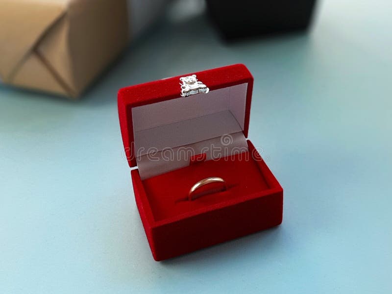 De rode doos van fluweeljuwelen met gouden ring op blauwe achtergrond stock afbeeldingen De rode doos van fluweeljuwelen met gouden ring op blauwe achtergrond stock afbeeldingen