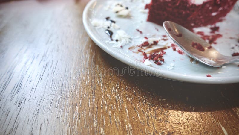 De rode rest van de fluweelcake op witte plaat op houten lijst, beëindigt dessert, vuile dessertplaat en lepel na maaltijd stock foto's De rode rest van de fluweelcake op witte plaat op houten lijst, beëindigt dessert, vuile dessertplaat en lepel na maaltijd stock foto's