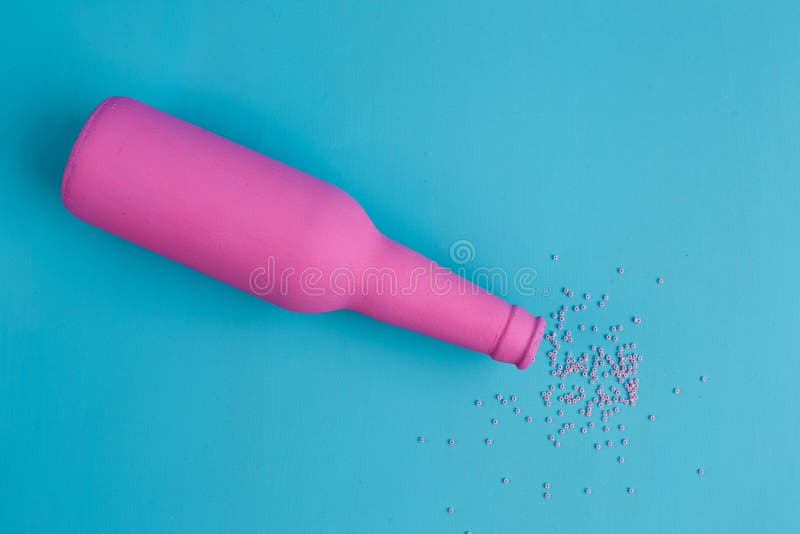 De roze fles en de bestrooide parels op blauwe achtergrond, vlakte lagen Al stock foto's De roze fles en de bestrooide parels op blauwe achtergrond, vlakte lagen Al stock foto's