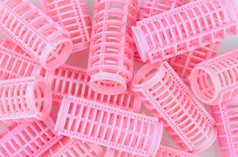 Plastic pink hair curlers in a random pattern that fills the frame. Plastic pink hair curlers in a random pattern that fills the frame.