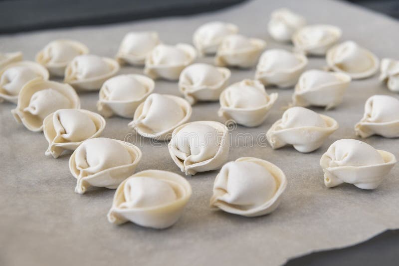 Dumplings, many  raw meat ravioli are on the baking sheet in rows , semifinished products. Dumplings, many  raw meat ravioli are on the baking sheet in rows , semifinished products