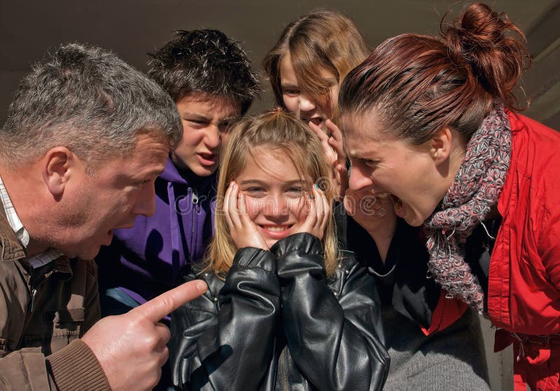 The whole family (father, mother, brother and sister) off - yell and threaten a young girl with blond hair. She put her hands on his ears and smiles and does not accept what her family talking. Horizontal color photo. The whole family (father, mother, brother and sister) off - yell and threaten a young girl with blond hair. She put her hands on his ears and smiles and does not accept what her family talking. Horizontal color photo.