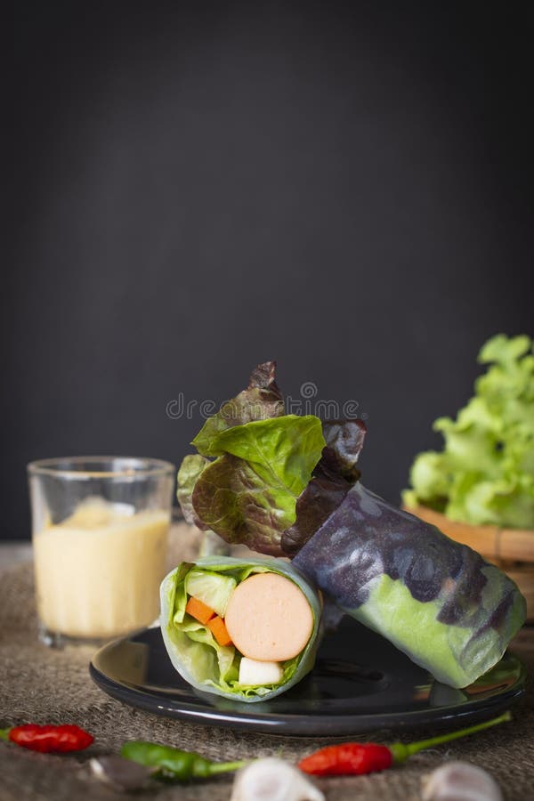 De saladebroodjes op zwarte die plaat op een zak met Spaanse pepers en knoflook wordt geplaatst worden geplaatst voor daar is sla stock foto's De saladebroodjes op zwarte die plaat op een zak met Spaanse pepers en knoflook wordt geplaatst worden geplaatst voor daar is sla stock foto's