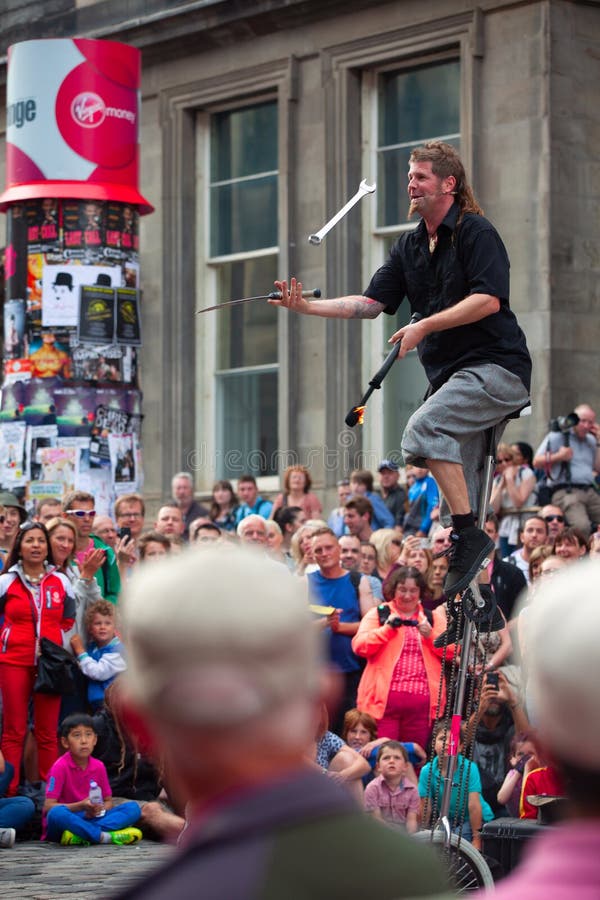 De saldi van de straatentertainer op unicycle en jongleert met met divers royalty-vrije stock foto De saldi van de straatentertainer op unicycle en jongleert met met divers royalty-vrije stock foto