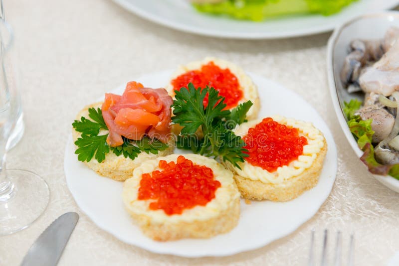 De sandwiches met rode kaviaar en zalm worden dicht omhoog uitgespreid op een plaat op een buffetlijst stock fotografie De sandwiches met rode kaviaar en zalm worden dicht omhoog uitgespreid op een plaat op een buffetlijst stock fotografie