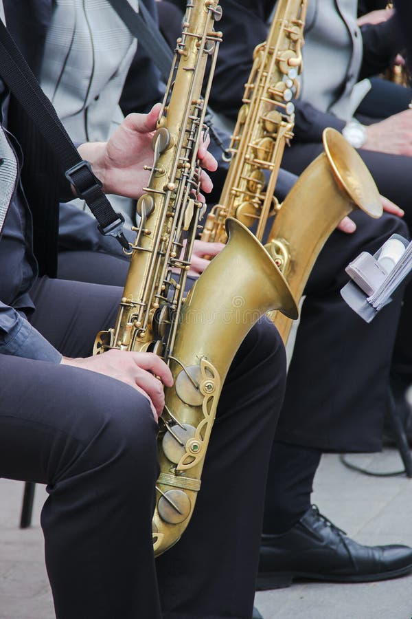 De saxofonisten die in een jazz spelen verbinden, gekleed in men& x27; s klassieke vest en broeken Sluit omhoog spruit van handen stock foto's De saxofonisten die in een jazz spelen verbinden, gekleed in men& x27; s klassieke vest en broeken Sluit omhoog spruit van handen stock foto's