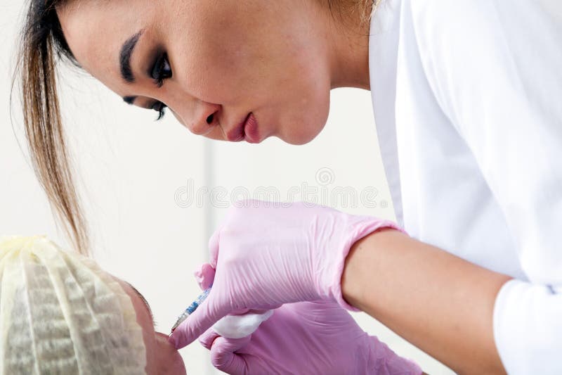 De schoonheidsspecialist duwt een spuit om Botox in te spuiten royalty-vrije stock afbeelding De schoonheidsspecialist duwt een spuit om Botox in te spuiten royalty-vrije stock afbeelding