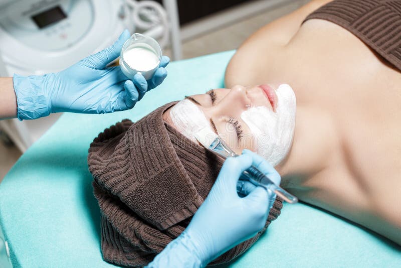 Beautician applies face mask on the beautiful young woman in Spa salon. cosmetic procedure skin care. Microdermabrasion. Beautician applies face mask on the beautiful young woman in Spa salon. cosmetic procedure skin care. Microdermabrasion