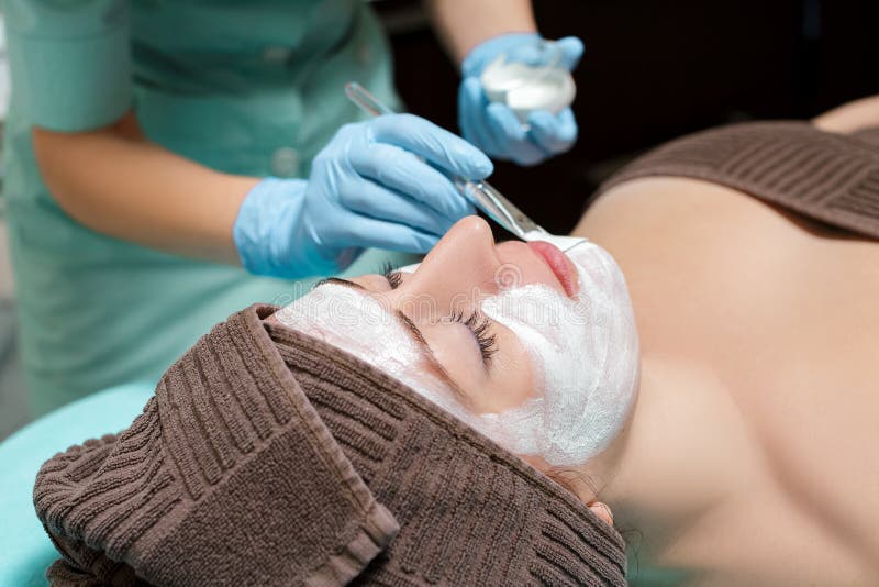 Beautician applies face mask on the beautiful young woman in Spa salon. cosmetic procedure skin care. Microdermabrasion. Beautician applies face mask on the beautiful young woman in Spa salon. cosmetic procedure skin care. Microdermabrasion