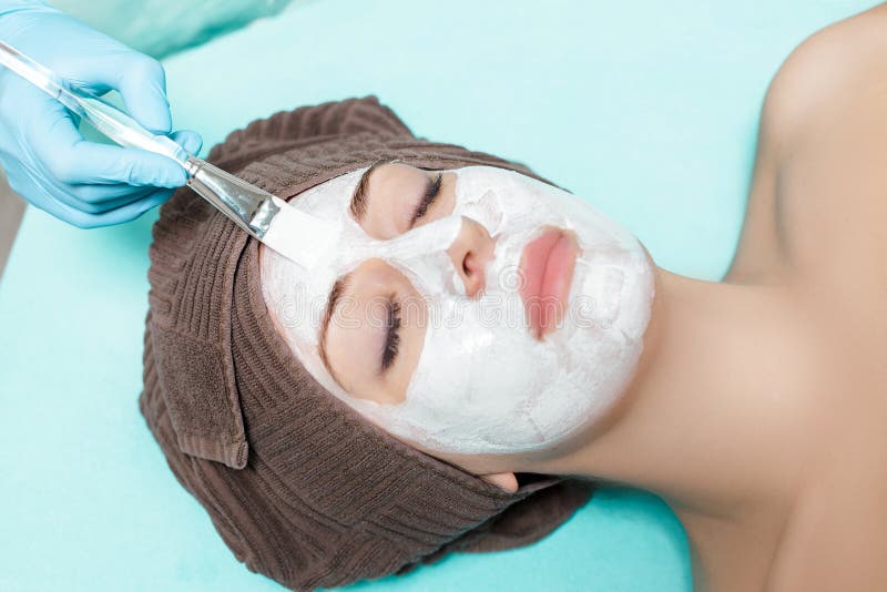 Beautician applies face mask on the beautiful young woman in Spa salon. cosmetic procedure skin care. Microdermabrasion. Beautician applies face mask on the beautiful young woman in Spa salon. cosmetic procedure skin care. Microdermabrasion