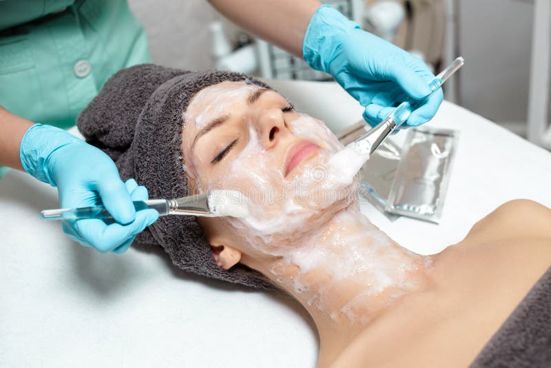 Beautician applies face mask on the beautiful young woman in Spa salon. cosmetic procedure skin care. Microdermabrasion. Beautician applies face mask on the beautiful young woman in Spa salon. cosmetic procedure skin care. Microdermabrasion