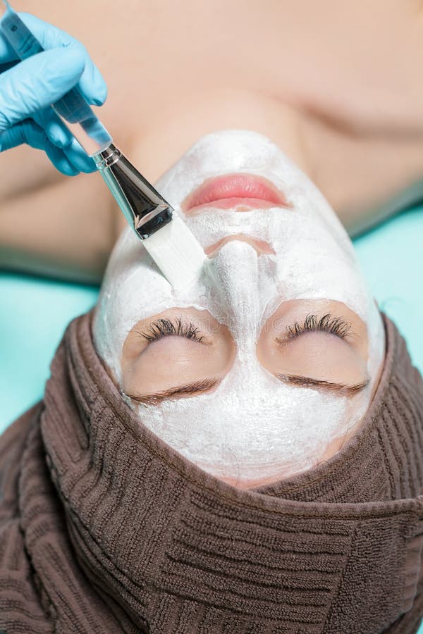 Beautician applies face mask on the beautiful young woman in Spa salon. cosmetic procedure skin care. Microdermabrasion. Beautician applies face mask on the beautiful young woman in Spa salon. cosmetic procedure skin care. Microdermabrasion