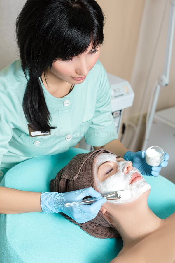 Beautician applies face mask on the beautiful young women in Spa salon. cosmetic procedure skin care. Microdermabrasion. Beautician applies face mask on the beautiful young women in Spa salon. cosmetic procedure skin care. Microdermabrasion