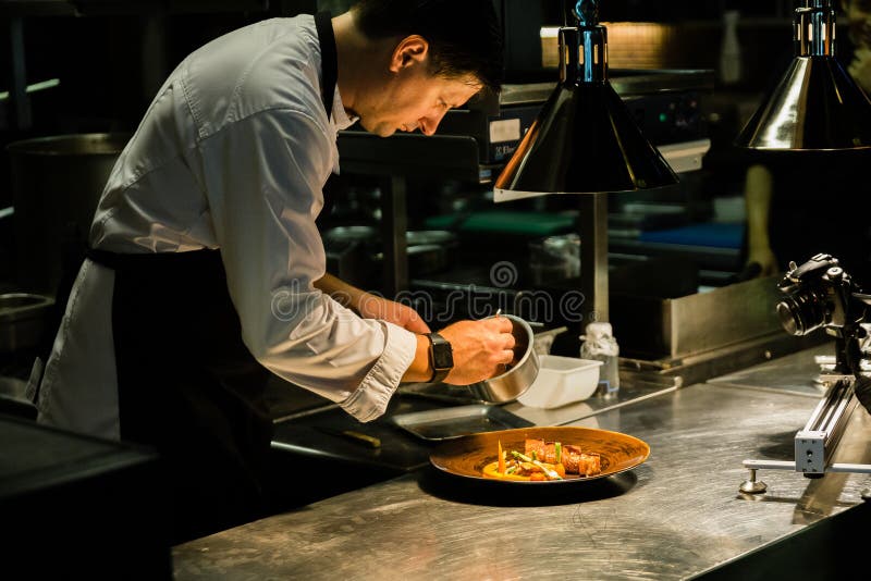 De schotel van het chef-kokplateren op keukenteller terwijl opname bij keukenhotel stock afbeeldingen De schotel van het chef-kokplateren op keukenteller terwijl opname bij keukenhotel stock afbeeldingen
