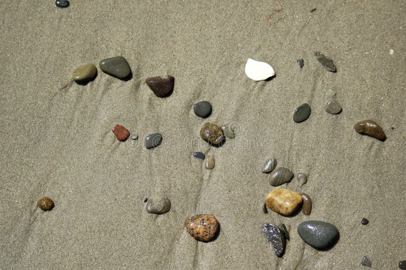 De scène van het strand - kiezelstenen in het zand royalty-vrije stock afbeeldingen De scène van het strand - kiezelstenen in het zand royalty-vrije stock afbeeldingen