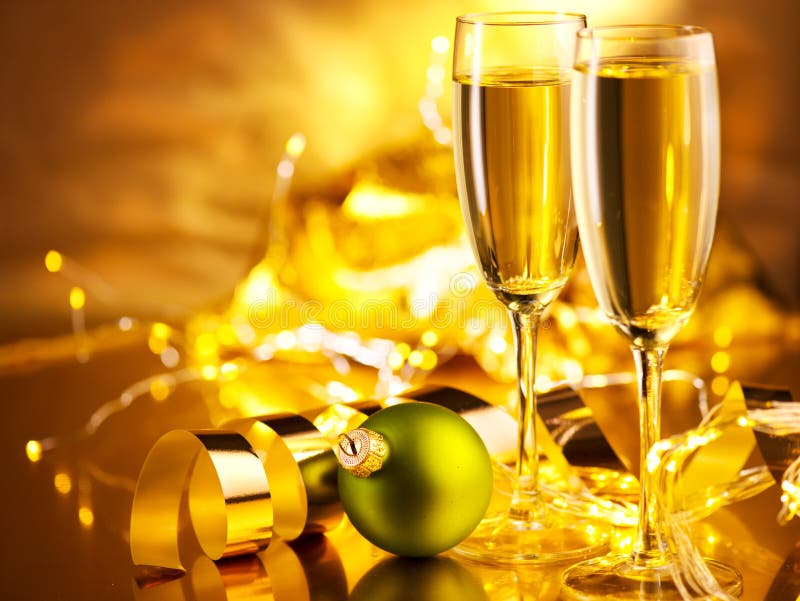 Christmas scene. Holiday champagne over golden glow background. Christmas and New Year celebration. Two flutes with sparkling wine over holiday bokeh blinking background. Christmas scene. Holiday champagne over golden glow background. Christmas and New Year celebration. Two flutes with sparkling wine over holiday bokeh blinking background