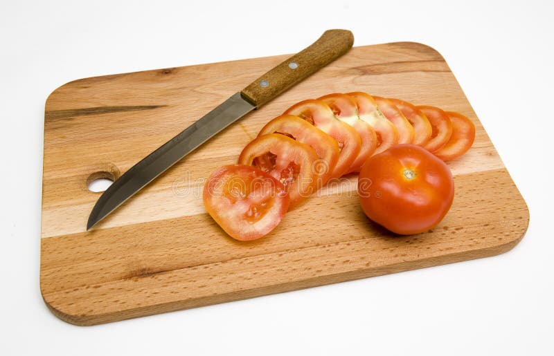 Sliced and whole tomatoes with knife on wooden chopping board, isolated on white background. Sliced and whole tomatoes with knife on wooden chopping board, isolated on white background.