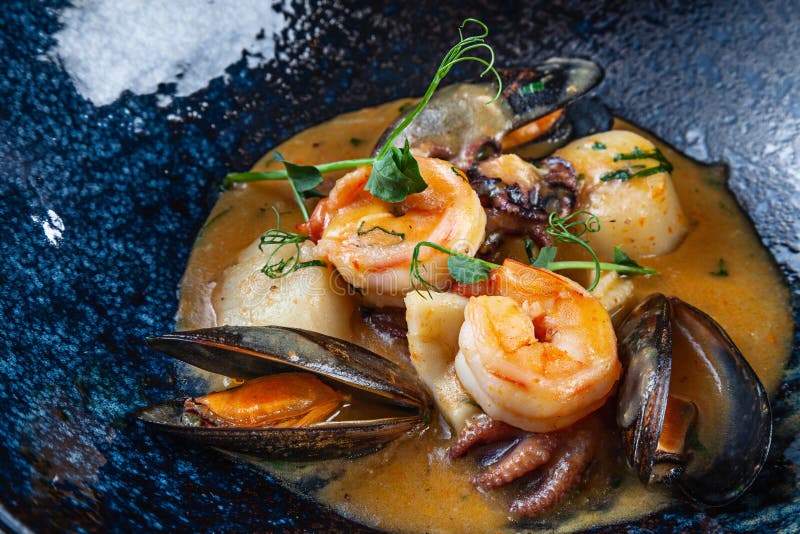 De selectieve nadruk op smakelijk sauteed zeevruchten in een romige saus Garnalen, kammosselen, mosselen, octopus in een donkere stock afbeeldingen De selectieve nadruk op smakelijk sauteed zeevruchten in een romige saus Garnalen, kammosselen, mosselen, octopus in een donkere stock afbeeldingen