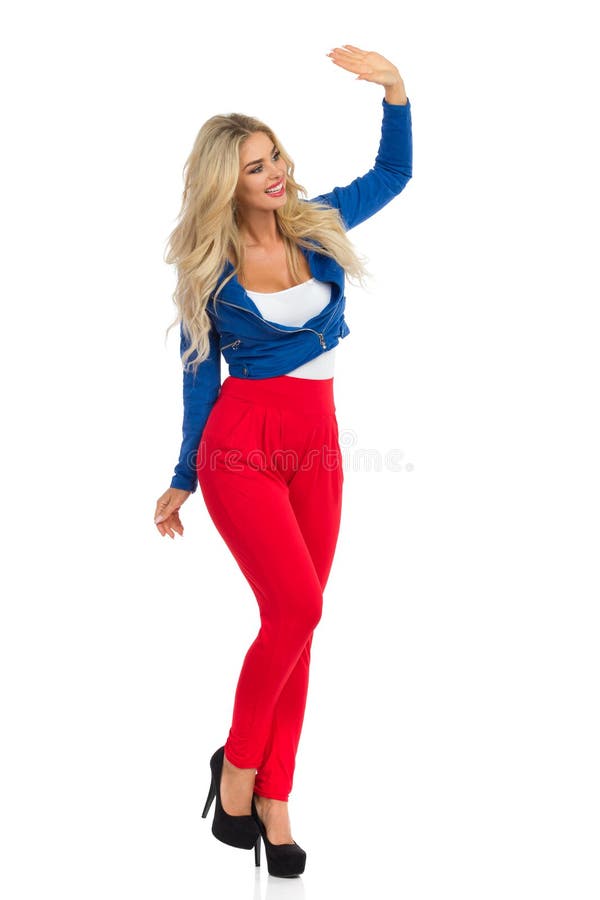 De sexy Blonde Vrouw in Jasje, Rode Broek en Hoge Hielen bevindt zich en golft stock foto's De sexy Blonde Vrouw in Jasje, Rode Broek en Hoge Hielen bevindt zich en golft stock foto's