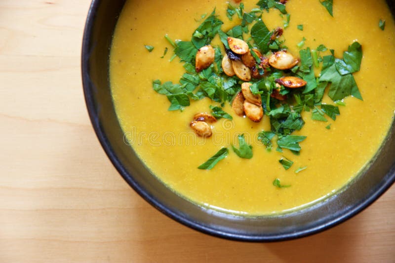 De soep van de Puréedwortel in kom met pompoenzaden en peterselie stock afbeelding De soep van de Puréedwortel in kom met pompoenzaden en peterselie stock afbeelding