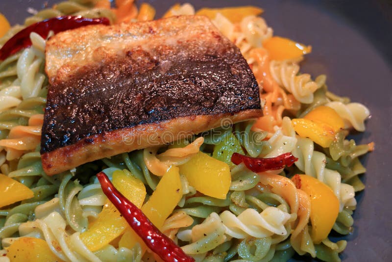De spiraal vormde deegwaren met knoflook, droge rode Spaanse peper, gele die peper en olijfolie met geroosterde Zalm wordt bedekt stock afbeeldingen De spiraal vormde deegwaren met knoflook, droge rode Spaanse peper, gele die peper en olijfolie met geroosterde Zalm wordt bedekt stock afbeeldingen