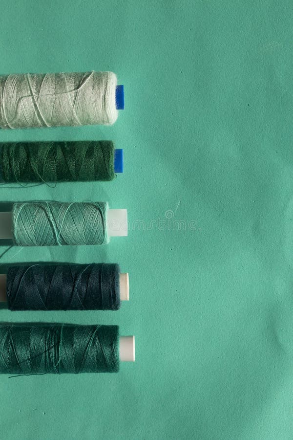 De spoelen van verschillende kleuren worden geschikt op een rij op een turkooise achtergrond In de stijl van vlakte lag stock foto De spoelen van verschillende kleuren worden geschikt op een rij op een turkooise achtergrond In de stijl van vlakte lag stock foto