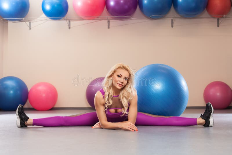 De sportvrouw zit op een streng Atletisch meisje die uitrekkende oefening in de geschiktheidsruimte doen stock foto's De sportvrouw zit op een streng Atletisch meisje die uitrekkende oefening in de geschiktheidsruimte doen stock foto's