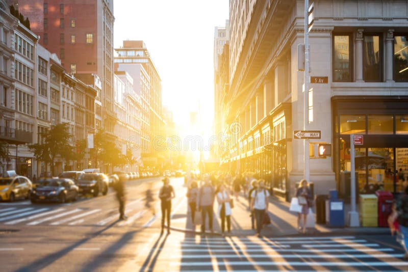 New York City - Bright light of sunset shines on crowds of people crossing the intersection on 5th Avenue in Manhattan, New York City. New York City - Bright light of sunset shines on crowds of people crossing the intersection on 5th Avenue in Manhattan, New York City