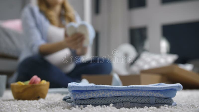 De stapel van babykleren met defocused zwangere vrouw