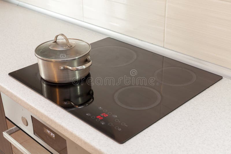 De steelpan van het metaalstaal in moderne keuken met inductiefornuis royalty-vrije stock foto De steelpan van het metaalstaal in moderne keuken met inductiefornuis royalty-vrije stock foto