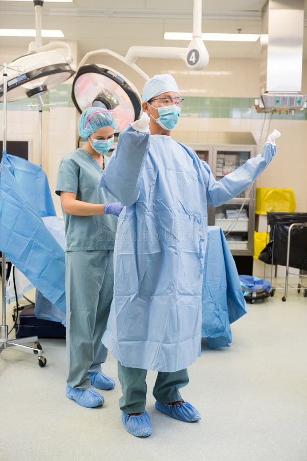 De Steriele Toga van verpleegstersassisting surgeon with stock afbeelding De Steriele Toga van verpleegstersassisting surgeon with stock afbeelding