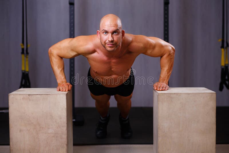 De sterke gescheurde kale mens werkt uit Bodybuilder die opdrukoefeningen in g doen stock fotografie De sterke gescheurde kale mens werkt uit Bodybuilder die opdrukoefeningen in g doen stock fotografie