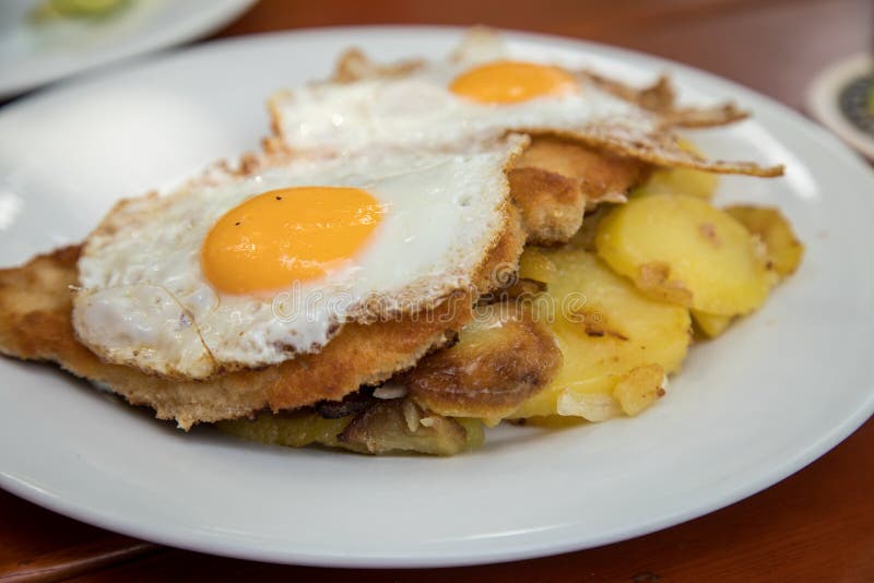 De stijl van de Schnitzelhamburg van het varkensvleesvlees met gebraden eieren en braadstukaardappels in Biergarten-restaurant royalty-vrije stock fotografie De stijl van de Schnitzelhamburg van het varkensvleesvlees met gebraden eieren en braadstukaardappels in Biergarten-restaurant royalty-vrije stock fotografie