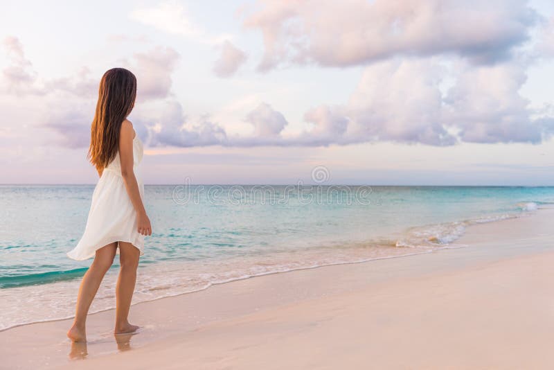 De stille vrouw die van het vakantieparadijs op zonsondergangstrand met pastelkleurenhemel en oceaan voor rust en sereniteit lopen