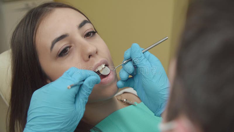 De tandarts onderzoekt een vrouwelijke patiënt in het tandbureau