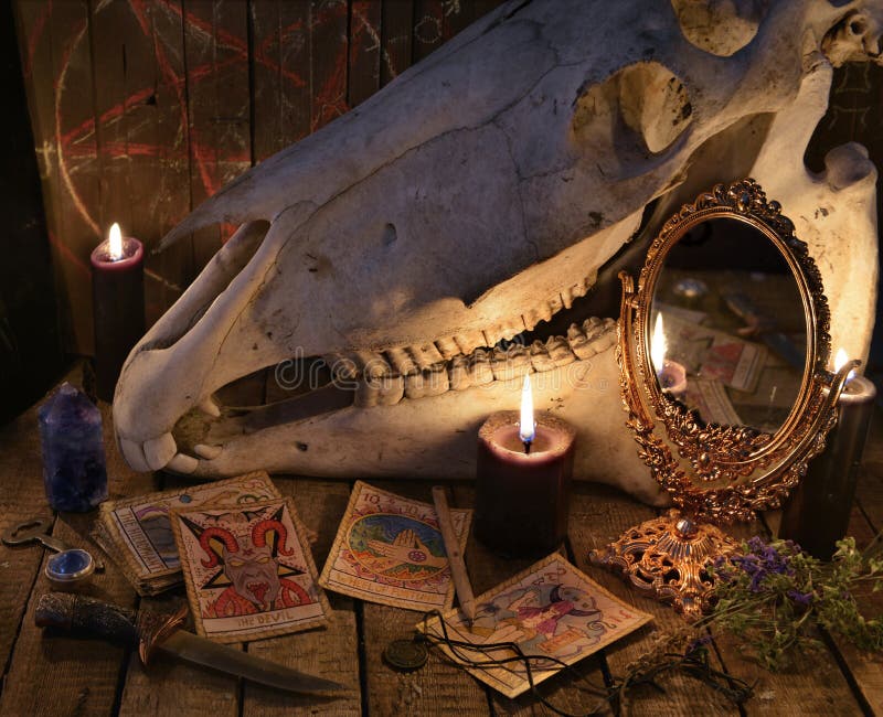 De Tarotkaarten, de magische spiegel en de paardschedel tegen de planken met pentagram stock foto De Tarotkaarten, de magische spiegel en de paardschedel tegen de planken met pentagram stock foto
