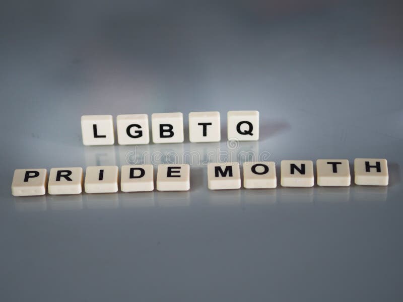 Wording LGBTQ Pride month text in plastic English letters are stamped onto a plastic sheet reflected on the glass table environment. Wording LGBTQ Pride month text in plastic English letters are stamped onto a plastic sheet reflected on the glass table environment