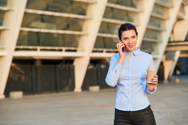De telefoon en de kop van de onderneemsterholding royalty-vrije stock fotografie De telefoon en de kop van de onderneemsterholding royalty-vrije stock fotografie