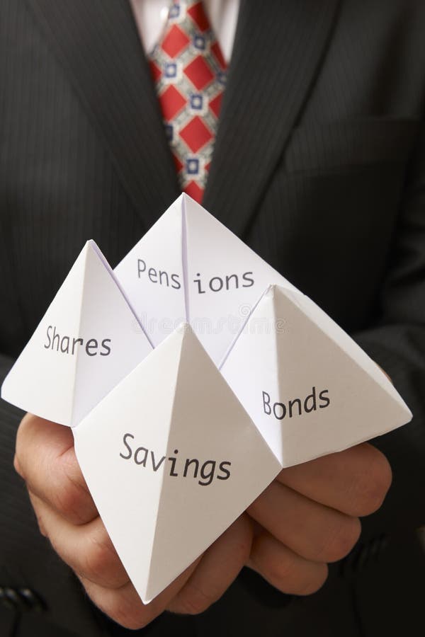Business man holding paper origami fortune teller with savings,bonds,shares and pensions written on it. Business man holding paper origami fortune teller with savings,bonds,shares and pensions written on it