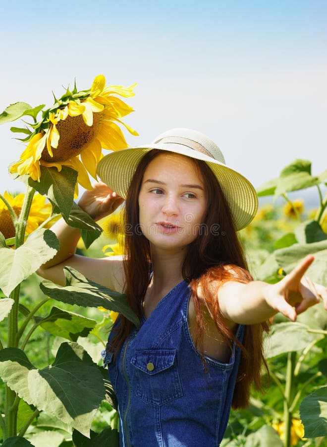 De tiener in denimkleding met glimlach toont op zonnebloem Landbouw gebied Portret stock foto's De tiener in denimkleding met glimlach toont op zonnebloem Landbouw gebied Portret stock foto's