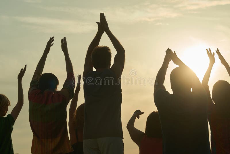 Applauding people silhouette. Rear back view handclapping family against morning sunrise. Applauding people silhouette. Rear back view handclapping family against morning sunrise.