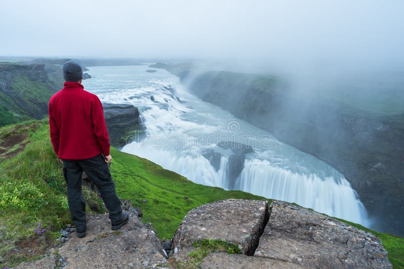 De toerist bekijkt de Gullfoss-waterval in IJsland stock afbeelding De toerist bekijkt de Gullfoss-waterval in IJsland stock afbeelding